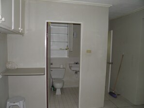 Bathroom features a toilet, sink, and shelf.
