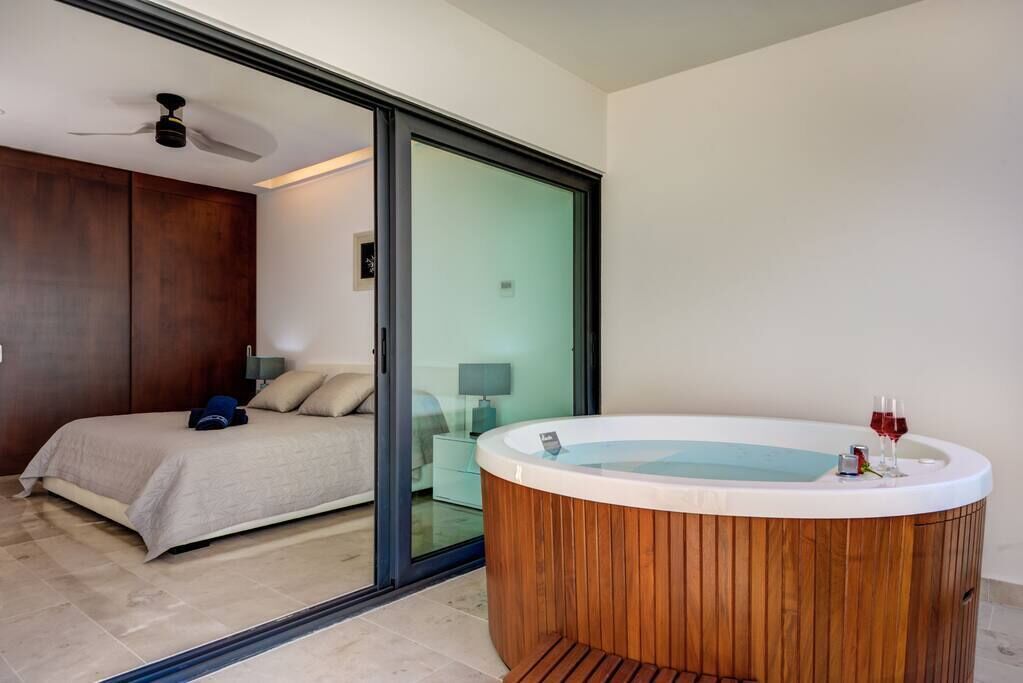 Ein Schlafzimmer mit Bett, einer Holzbadewanne und einer Schiebetür zu einem Badezimmer.