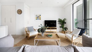 Una sala de estar moderna con sofá, mesa de centro, televisor y plantas.