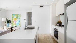 Una cocina moderna con armarios blancos, una isla central con un lavabo, una estufa y un horno.