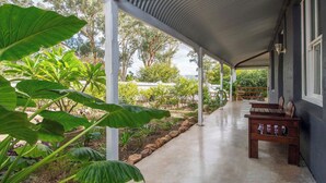 A covered outdoor area with a concrete floor, wooden benches, and large green plants. - Perfect Location for Leisure or Business - Right in the main street (Scone)