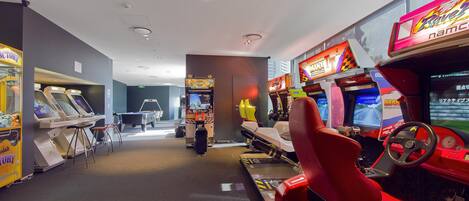 A row of racing game machines with a red racing seat in the foreground.