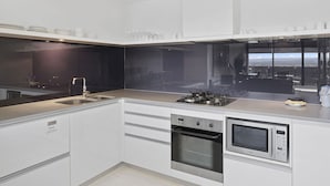 Una cucina moderna con piano cottura a gas, forno e microonde. Sono presenti mobili e un bancone.