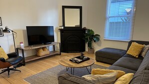 Een woonkamer met een televisie, open haard, bank en salontafel.