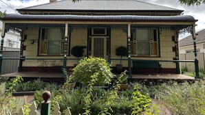 Een woonhuis met twee verdiepingen, een balkon, een voortuin en een kleine tuin.