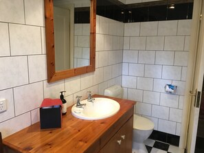 A bathroom with a wooden vanity, white sink, and a mirror.