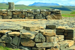 A stone wall with a wooden bench in a rural landscape. - A wonderful small and cosy house with a private natural hot tub, fantastic views (Skagafjörður)