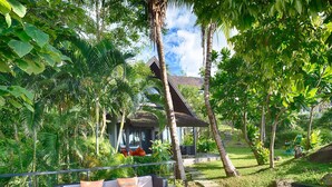 A deck with outdoor furniture, a pathway, and lush greenery. - Villa Yang-5 BR Luxury Villa(Butler,Chef,Transfer) (Kamala)