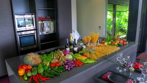 A kitchen counter with a variety of fresh produce, bottles of wine, and cooking utensils. - Villa Yang-5 BR Luxury Villa(Butler,Chef,Transfer) (Kamala)