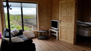 Una habitación acogedora con un ventanal grande, un sofá, un televisor y una cama.