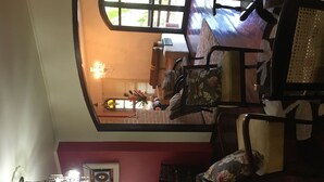A dining area with a high ceiling, a chandelier, and a view of the kitchen through a window. - Vacation home 4 Palmeiras  (Figueira)