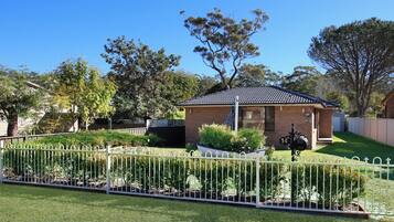 A beach house with a fenced yard and a small patio area.