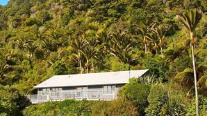 A house with a balcony, surrounded by lush greenery and hills. - Home by the Beach with sensational view! Pet-friendly. (Westport)
