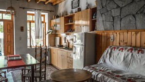 Eine rustikale Küche mit Holzschnitzschränken, einem Kühlschrank und einem Essbereich mit Tisch und Stühlen.