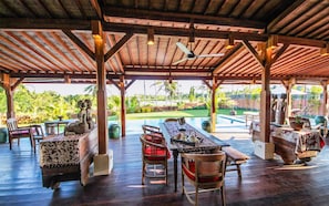 Relax in a serene outdoor dining area surrounded by lush greenery and a pool.