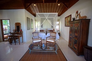Cozy retreat with a bed, two chairs, and a wooden cabinet, set against a warm backdrop.