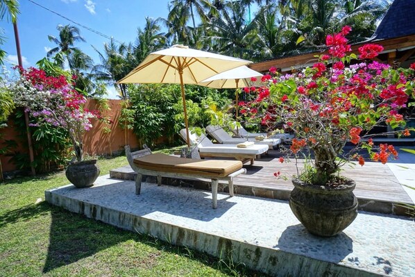 Relax in a serene outdoor space surrounded by lush greenery and flowering plants.