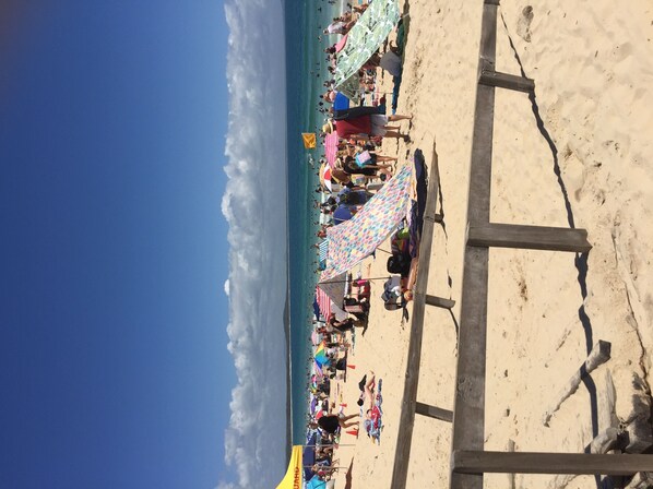 Guests can enjoy the beach with umbrellas and a lifeguard tower nearby.