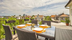 A dining area with a table set for four, outdoor seating, and a view of the neighborhood.