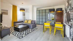 A modern living room with a sectional sofa, a glass coffee table, and a dining area with yellow chairs.