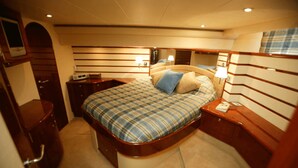 A compact, well-lit bedroom with a bed, bedside tables, and a small desk.