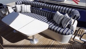 A boat deck with a white table and striped cushions.