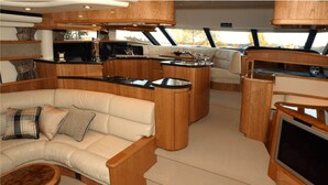 A yacht interior with a sofa, a dining area, and a TV.