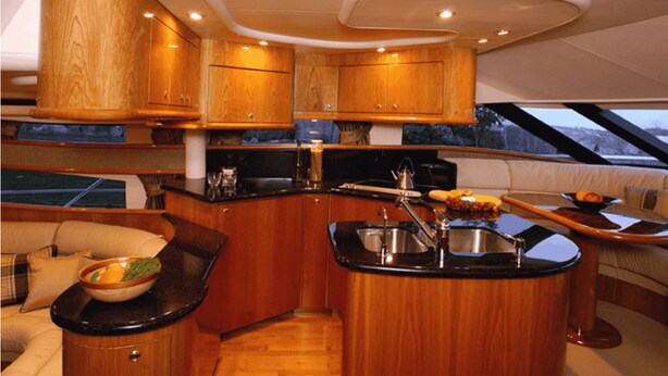 A compact kitchen with wooden cabinets, a central island with a sink, and a dining area with a bench.