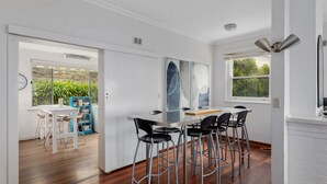 A modern kitchen with a bar area, wooden flooring, and a view of the outdoors.