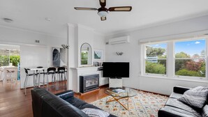 A modern living room with a fireplace, a flat-screen TV, and a dining area with bar stools.