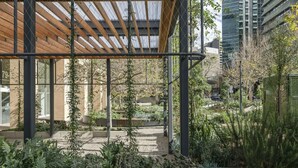 A modern building with a covered outdoor area featuring a wooden pergola, stone pathways, and various plants. - North Sydney - BS901 Berry Street - Modern 1BR with Balcony in the Heart of North Sydney CBD (North Sydney)