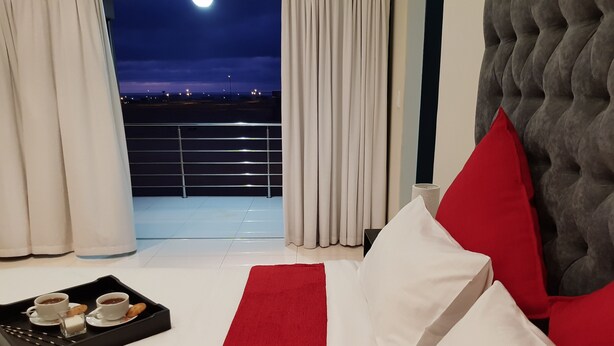 A hotel room with a balcony, a bed with white and red bedding, and a tray with cups and pastries. - Seboa Accommodation (Guesthouse and Self Catering) (Vineta)