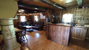 L’intérieur d’un chalet rustique, avec un plancher en bois, un coin bar et un espace repas comprenant une table et des chaises.