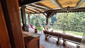 Une terrasse en bois avec un banc et une table, donnant sur une zone boisée.