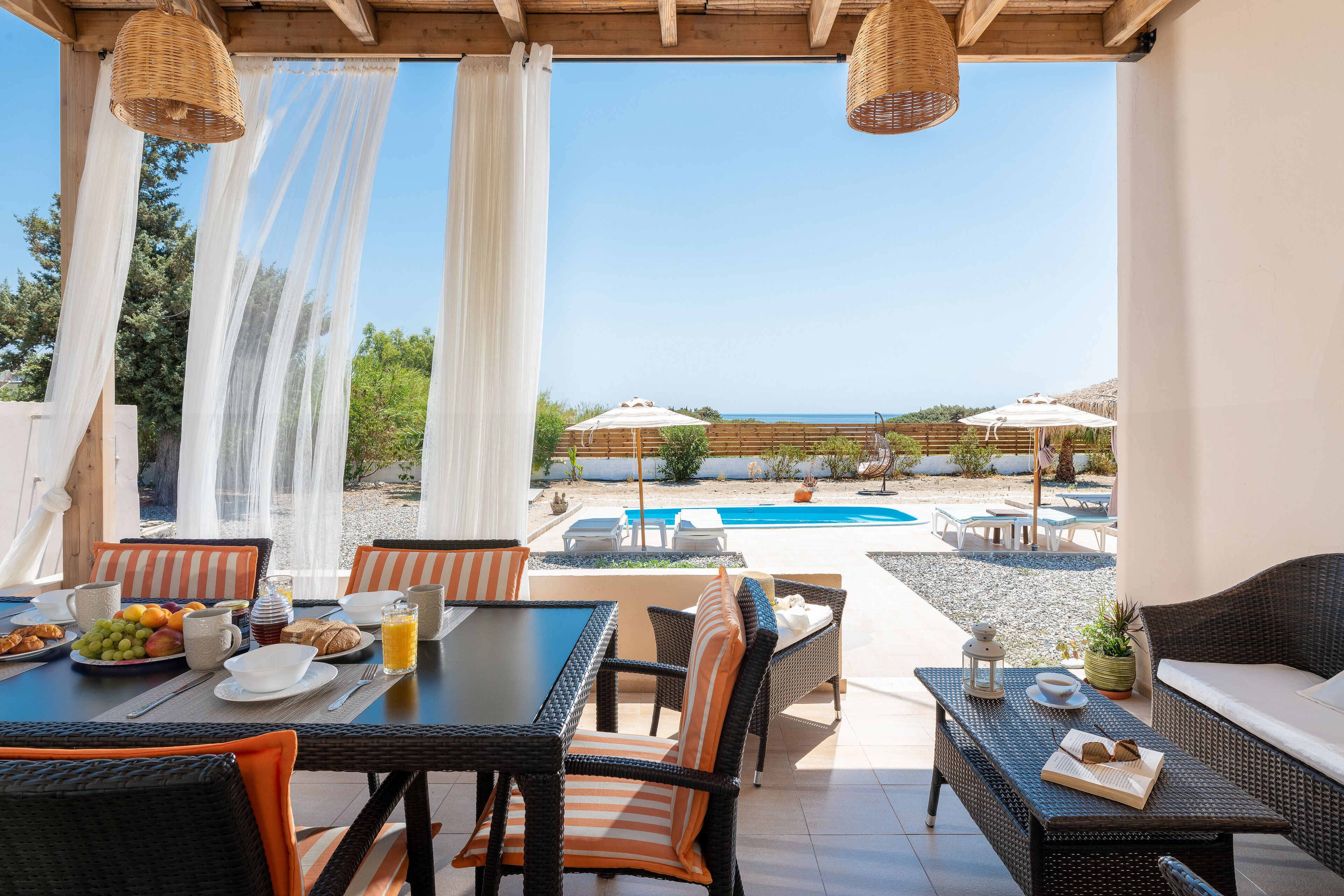 A patio with a dining table, chairs, and a pool area in the background.