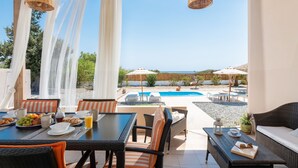 Un patio con una mesa de comedor, sillas y una zona de piscina al fondo.