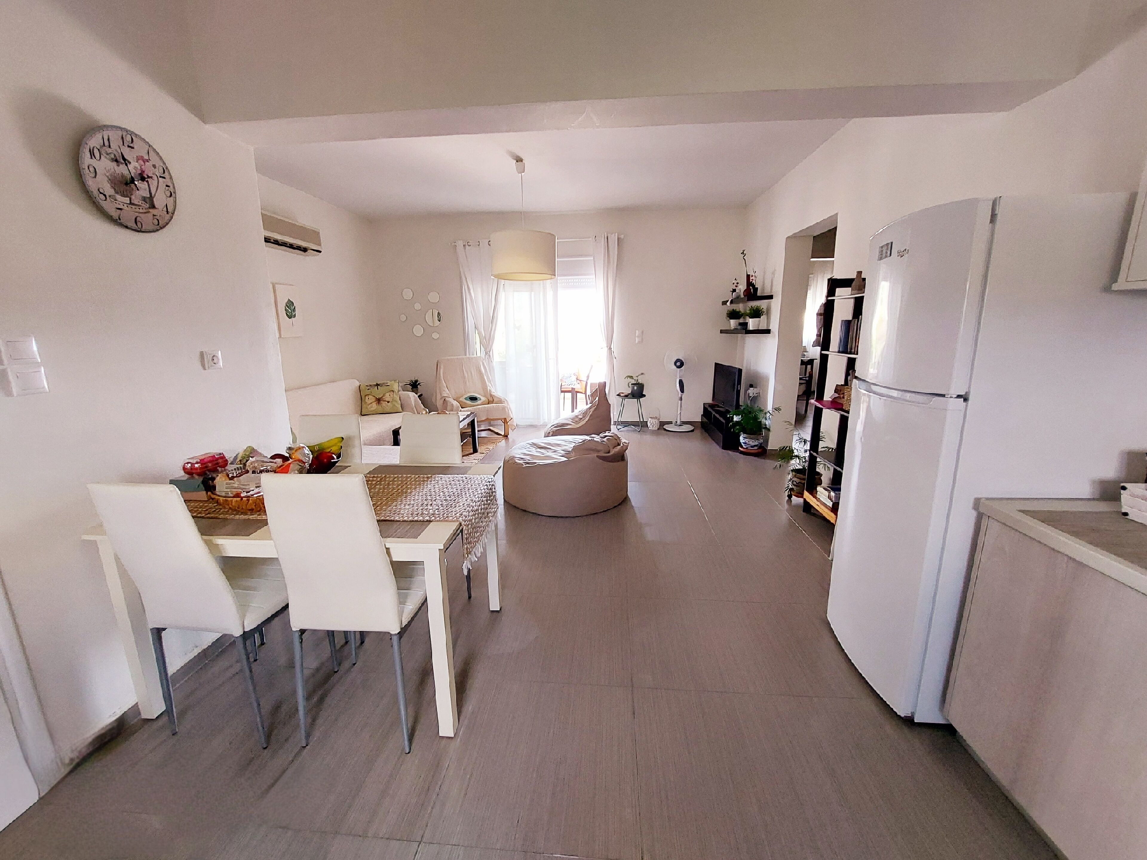Een moderne keuken met een eethoek, witte meubels en een koelkast.