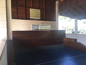 Relax in the cozy seating area with a wooden bench and wall-mounted sign displaying the establishment's hours.