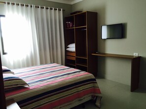 Relax in a cozy space with a neatly made bed, a wardrobe, and a TV for your entertainment.