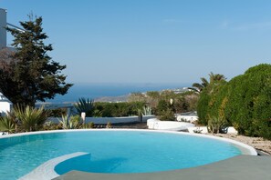 Piscina com vista para o mar e colinas.