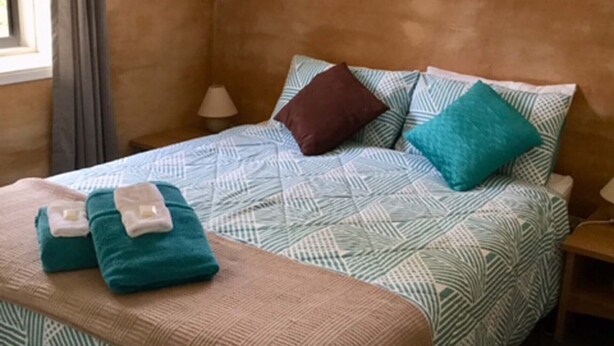 A bedroom with a patterned bedspread, pillows, and a blanket with a towel on the bed.