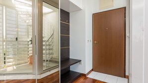Een modern interieur met een glazen deur die uitkomt op een balkon, een houten trap en een gesloten houten deur.