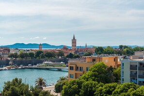 Une ville côtière dotée d’une tour imposante, d’un port de plaisance et d’immeubles avec des balcons.