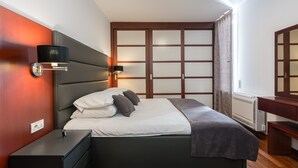 Een moderne slaapkamer met een bed, nachtkastjes, een wandlamp en een raam met gordijnen.