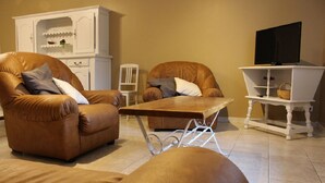 A living room with two brown leather armchairs, a wooden coffee table, a white cabinet, and a television on a stand. - Countryside house - Le Rochepot - Cote d'Or (La Rochepot)