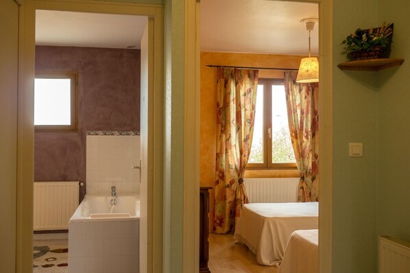 A room with a bathtub, a window with floral curtains, and a bed. - Countryside house - Le Rochepot - Cote d'Or (La Rochepot)