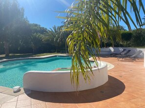 A swimming pool with a curved edge, surrounded by a tiled patio. - Superbe villa méditerranéenne spacieuse,lumineuse,calme, piscine, jacuzzi, parc, (Cabestany)