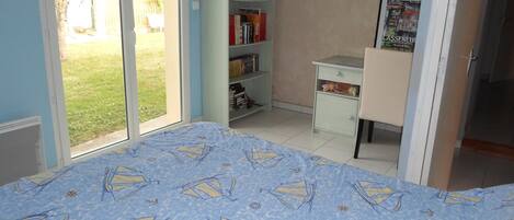 A bedroom with a bed, a desk, a bookshelf, and a door leading to a balcony.
