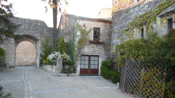 A courtyard with a cobblestone path, a stone archway, and a building with a wooden door. - Furnished one-storey villa with 8 sleepings with a private pool (Bias)