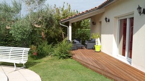 A patio with a wooden deck, outdoor furniture, and a small garden area. - Furnished one-storey villa with 8 sleepings with a private pool (Bias)